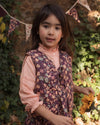 Early Sunday, Lou Vest jacket in Plum, made from Printed Cotton Satin fabric, featuring sleeveless quilted silhouette with tie-up bow detailing, shown in a front view of model playing outdoors