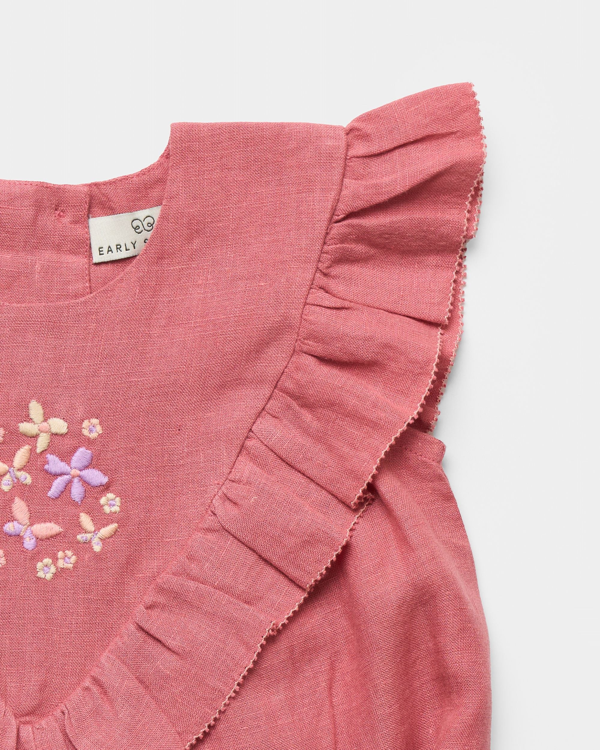 Early Sunday, Lucy Baby Bubble Romper in Peony color, made from 70% Cotton 30% Linen fabric, featuring a bubble pattern with beautiful embroidery, shown in a closeup flat-lay view