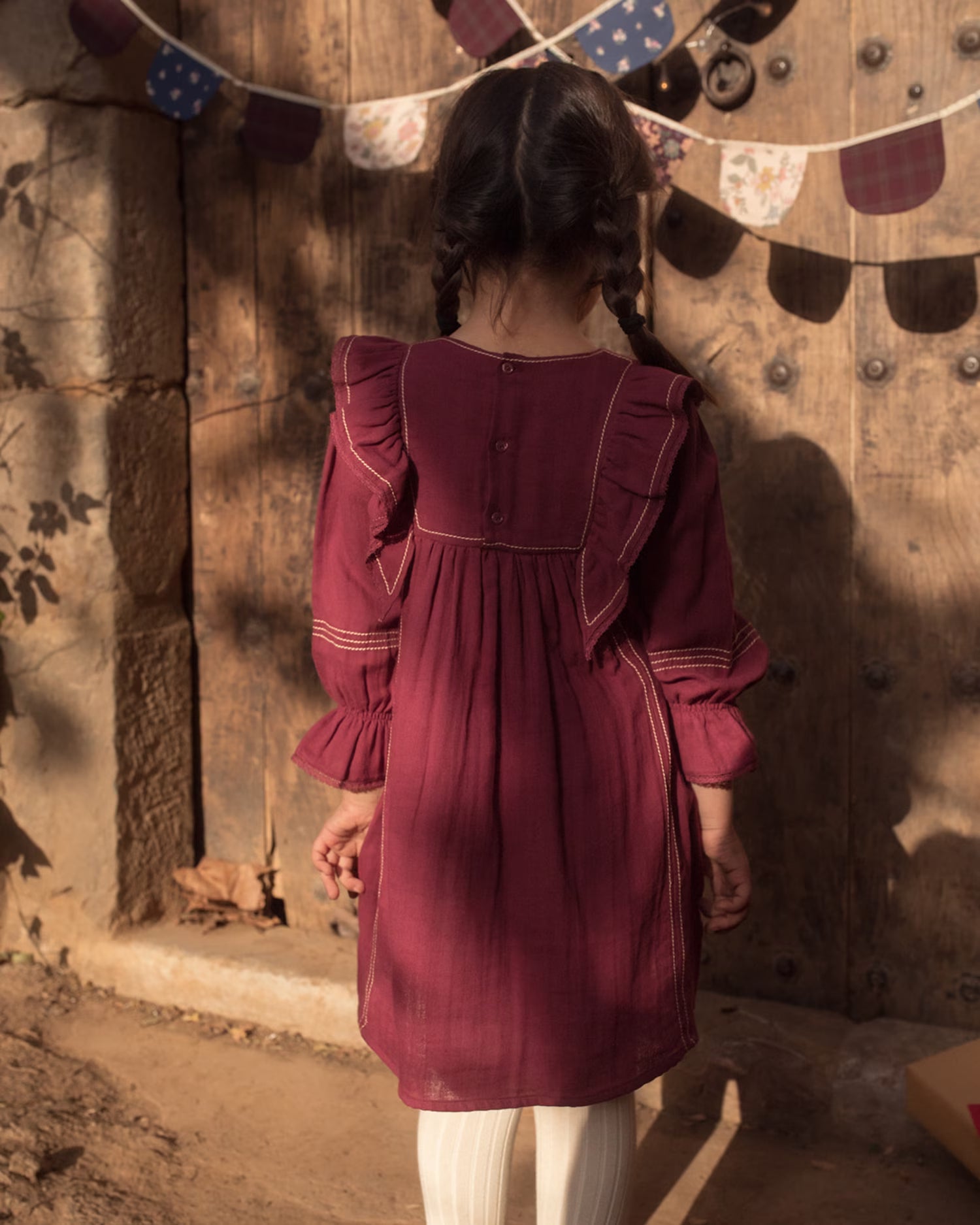 Early Sunday, Margot Dress in Plum, made from Cotton Double Gauze fabric, featuring classic silhouette with ruffle detailing around the sleeves, shown in a back view of model wearing it