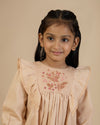 Early Sunday, Margot Dress in Beige, made from Cotton Satin fabric, featuring classic silhouette with floral embroidery around the yoke and ruffle detailing, shown in a front view of a model wearing it in a studio setting