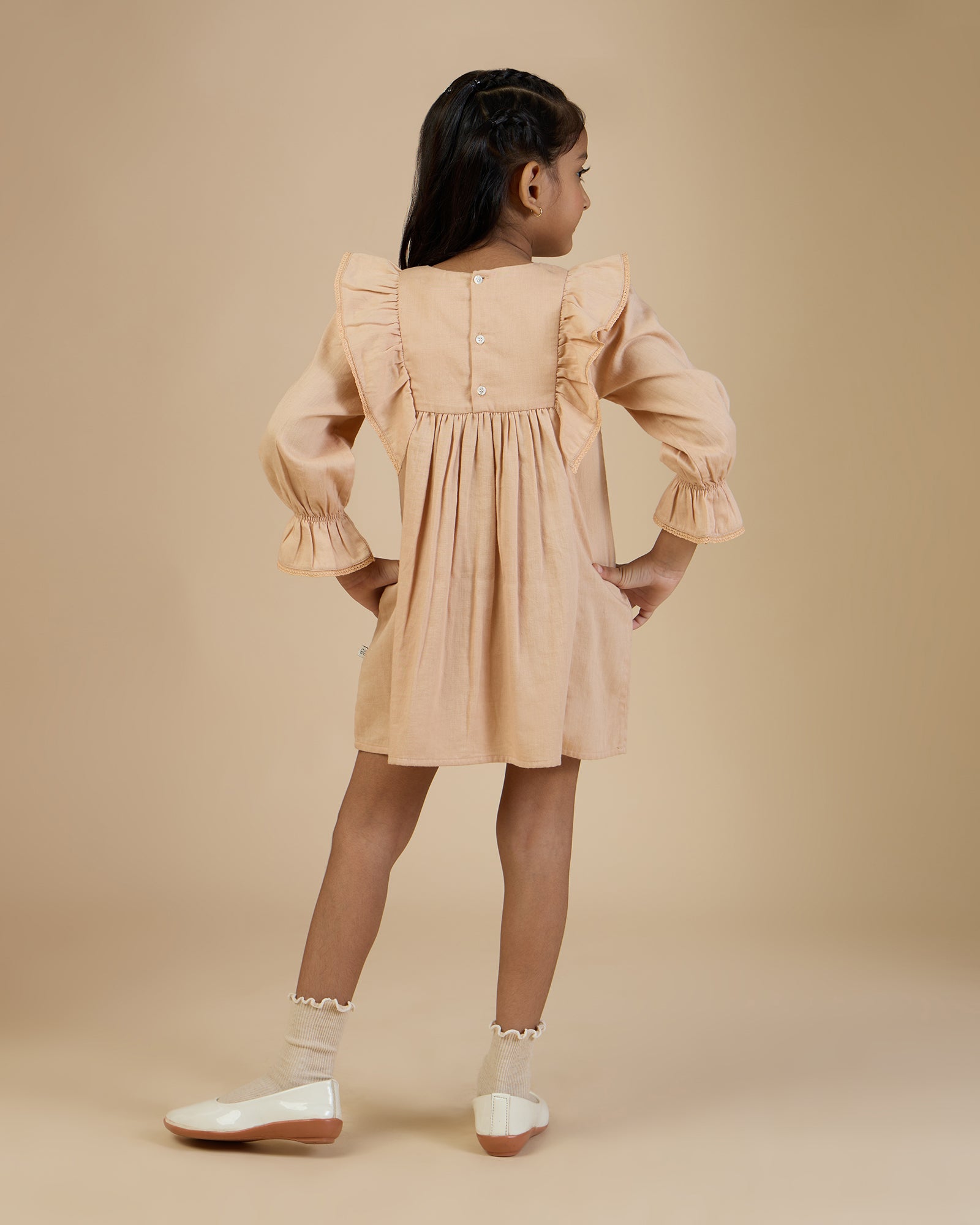 Early Sunday, Margot Dress in Beige, made from Cotton Satin fabric, featuring classic silhouette with floral embroidery around the yoke and ruffle detailing, shown in a back view of model wearing it