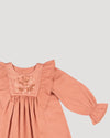 Early Sunday, Margot Dress in Earthy Pink, made from Cotton Satin fabric, featuring classic silhouette with floral embroidery around the yoke and ruffle detailing, shown in a closeup flat-lay view