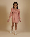 Early Sunday, Margot Dress in Earthy Pink, made from Cotton Satin fabric, featuring classic silhouette with floral embroidery around the yoke and ruffle detailing, shown in a front view of model wearing it