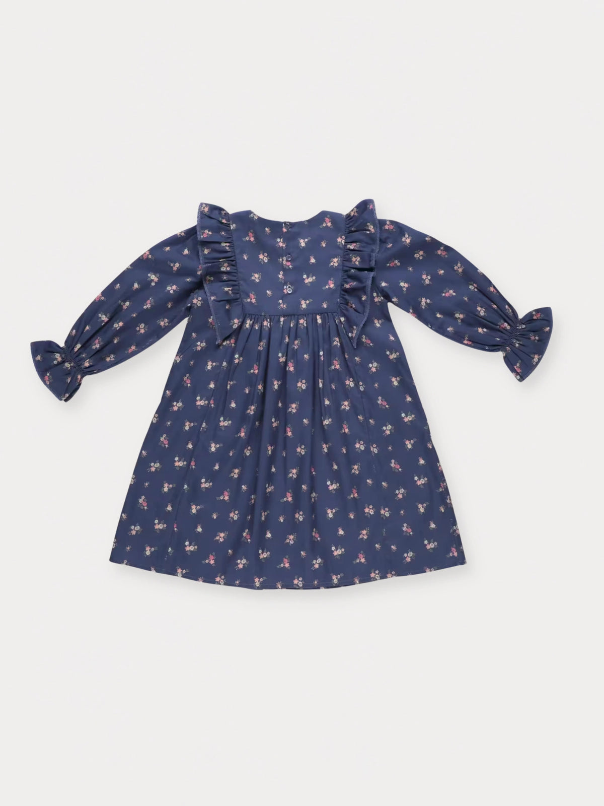Early Sunday, Margot Dress in Ditsy Bouquet Navy, made from Printed Cotton Satin fabric, featuring classic silhouette with ruffle detailing around the sleeves, shown in a back flat-lay view
