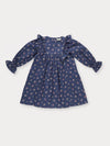 Early Sunday, Margot Dress in Ditsy Bouquet Navy, made from Printed Cotton Satin fabric, featuring classic silhouette with ruffle detailing around the sleeves, shown in a front flat-lay view