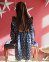 Early Sunday, Margot Dress in Ditsy Bouquet Navy, made from Printed Cotton Satin fabric, featuring classic silhouette with ruffle detailing around the sleeves, shown in a back view of model wearing it
