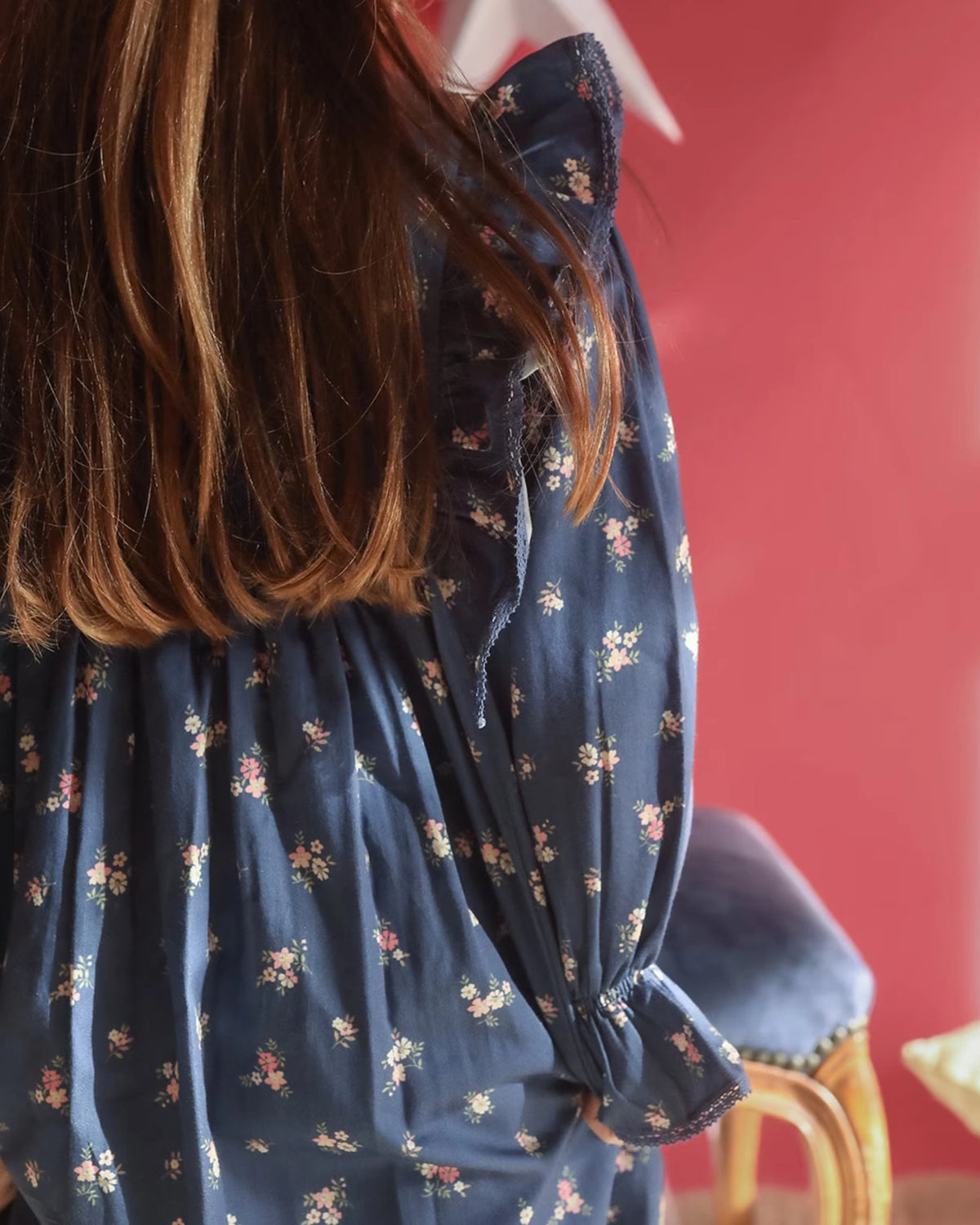 Early Sunday, Margot Dress in Ditsy Bouquet Navy, made from Printed Cotton Satin fabric, featuring classic silhouette with ruffle detailing around the sleeves, shown in a close up shot of model wearing it