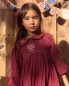 Early Sunday, Marguerite Dress in Plum, made from Cotton Double Gauze fabric, featuring floral embroidery with frilled Peter Pan collar, shown in a close up shot of model wearing it