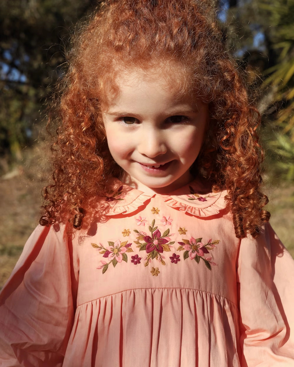 Early Sunday, Marguerite Dress in Blush Pink, made from Cotton Satin fabric, featuring floral embroidery with frilled Peter Pan collar, shown in a close up shot of model wearing it