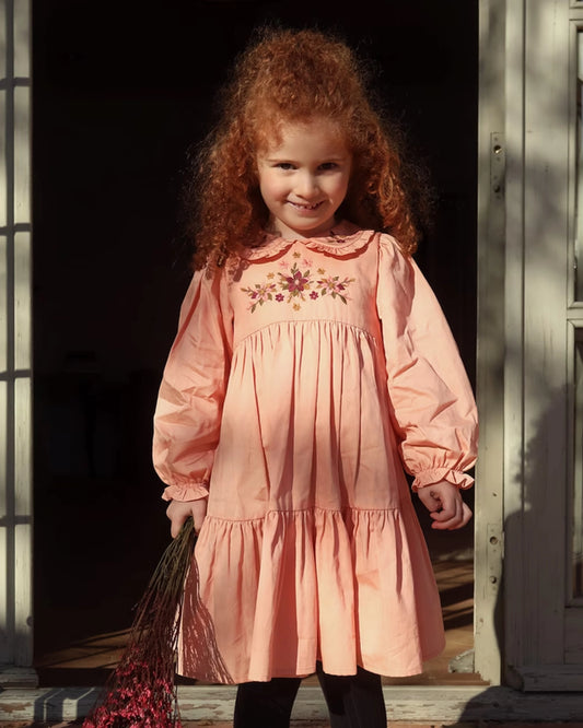 Early Sunday, Marguerite Dress in Blush Pink, made from Cotton Satin fabric, featuring floral embroidery with frilled Peter Pan collar, shown in a front view of model wearing outdoors