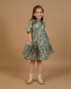 Early Sunday, Marguerite Dress in Autumn Bloom Soft Green, made from Printed Cotton Double Gauze fabric, featuring classic silhouette with a collar and ruffle detailing, shown in a front view of model wearing it