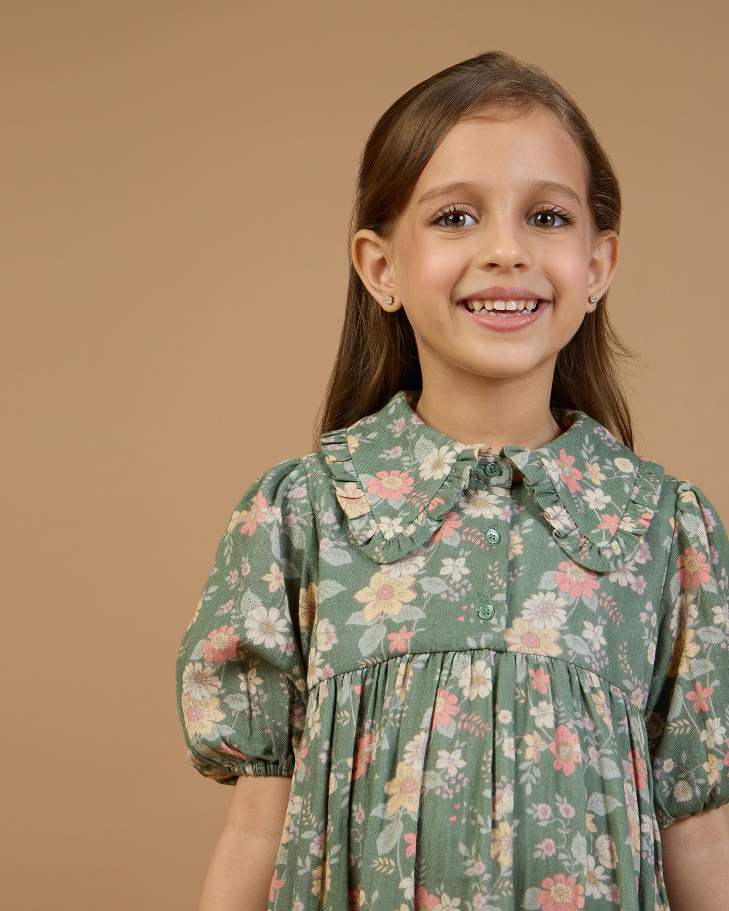 Early Sunday, Marguerite Dress in Autumn Bloom Soft Green, made from Printed Cotton Double Gauze fabric, featuring classic silhouette with a collar and ruffle detailing, shown in a front view of a model wearing it in a studio setting