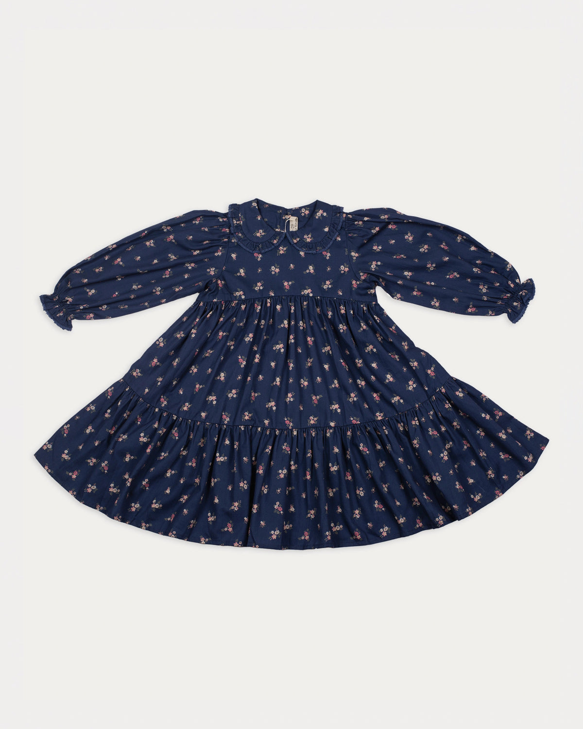 Early Sunday, Marguerite Dress in Ditsy Bouquet Navy, made from Printed Cotton Satin fabric, featuring gathered sleeves with frilled Peter Pan collar, shown in a front flat-lay view