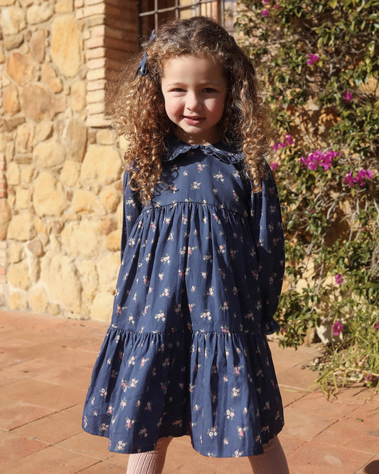 Early Sunday, Marguerite Dress in Ditsy Bouquet Navy, made from Printed Cotton Satin fabric, featuring gathered sleeves with frilled Peter Pan collar, shown in a front view of model wearing outdoors