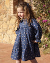 Early Sunday, Marguerite Dress in Ditsy Bouquet Navy, made from Printed Cotton Satin fabric, featuring gathered sleeves with frilled Peter Pan collar, shown in an angled view of a model wearing outdoors