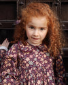 Early Sunday, Marguerite Dress in Garden Flowers Plum, made from Printed Cotton Satin fabric, featuring floral print and detailed lace yoke with Peter Pan collar, shown in a close up shot of model wearing it