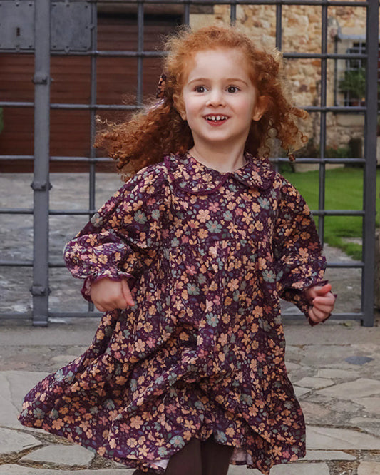 Early Sunday, Marguerite Dress in Garden Flowers Plum, made from Printed Cotton Satin fabric, featuring floral print and detailed lace yoke with Peter Pan collar, shown in a front view of model wearing it