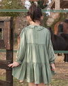 Early Sunday, Marguerite Dress in Sage Green, made from Viscose Drapey Twill fabric, featuring floral embroidery with frilled Peter Pan collar and gathered sleeves, shown in a back view of model wearing outdoors