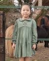 Early Sunday, Marguerite Dress in Sage Green, made from Viscose Drapey Twill fabric, featuring floral embroidery with frilled Peter Pan collar and gathered sleeves, shown in a front view of model wearing outdoors
