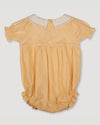 Early Sunday, Matilda Baby Bubble Romper in Vanilla color, made from Cotton Dobby Swiss Dots fabric, featuring ruffled neckline for a delicate touch and elasticated leg openings for a comfortable fit, shown in a back flat-lay view