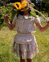 Early Sunday, Melissa Skirt in Emma Floral Mint color, made from Organic Printed Cotton Cambric fabric, featuring tiered frilly skirt with smocked waistband, shown in a front view of model playing outdoors