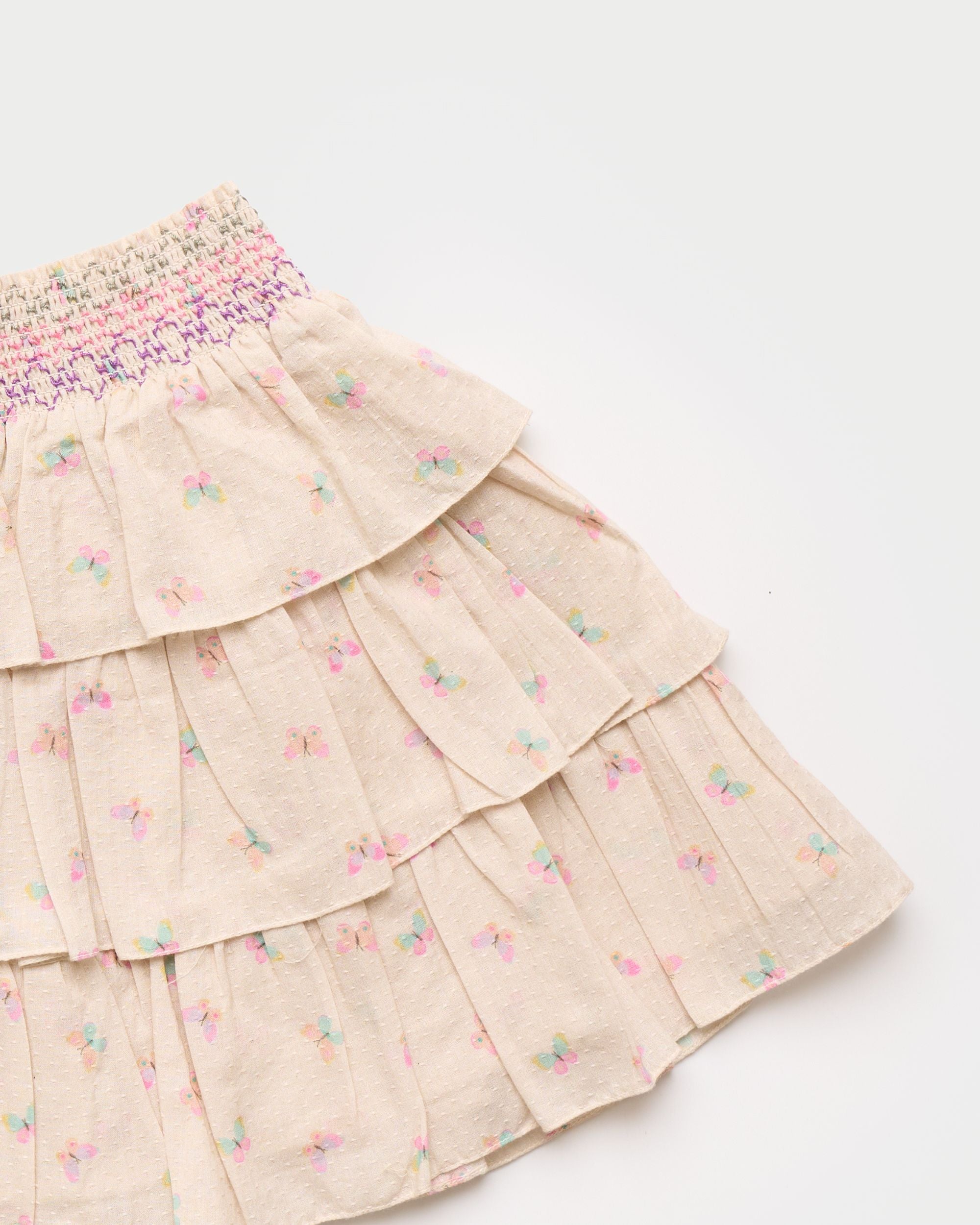 Early Sunday, Melissa Skirt in Butterflies print, made from Printed Cotton Tiny Swiss Dobby fabric, featuring tiered frilly skirt with smocked waistband, shown in a closeup flat-lay view