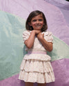 Early Sunday, Melissa Skirt in Butterflies print, made from Printed Cotton Tiny Swiss Dobby fabric, featuring tiered frilly skirt with smocked waistband, shown in a front view of model wearing outdoors