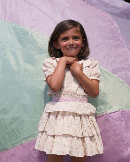 Early Sunday, Melissa Skirt in Butterflies print, made from Printed Cotton Tiny Swiss Dobby fabric, featuring tiered frilly skirt with smocked waistband, shown in a front view of model wearing outdoors