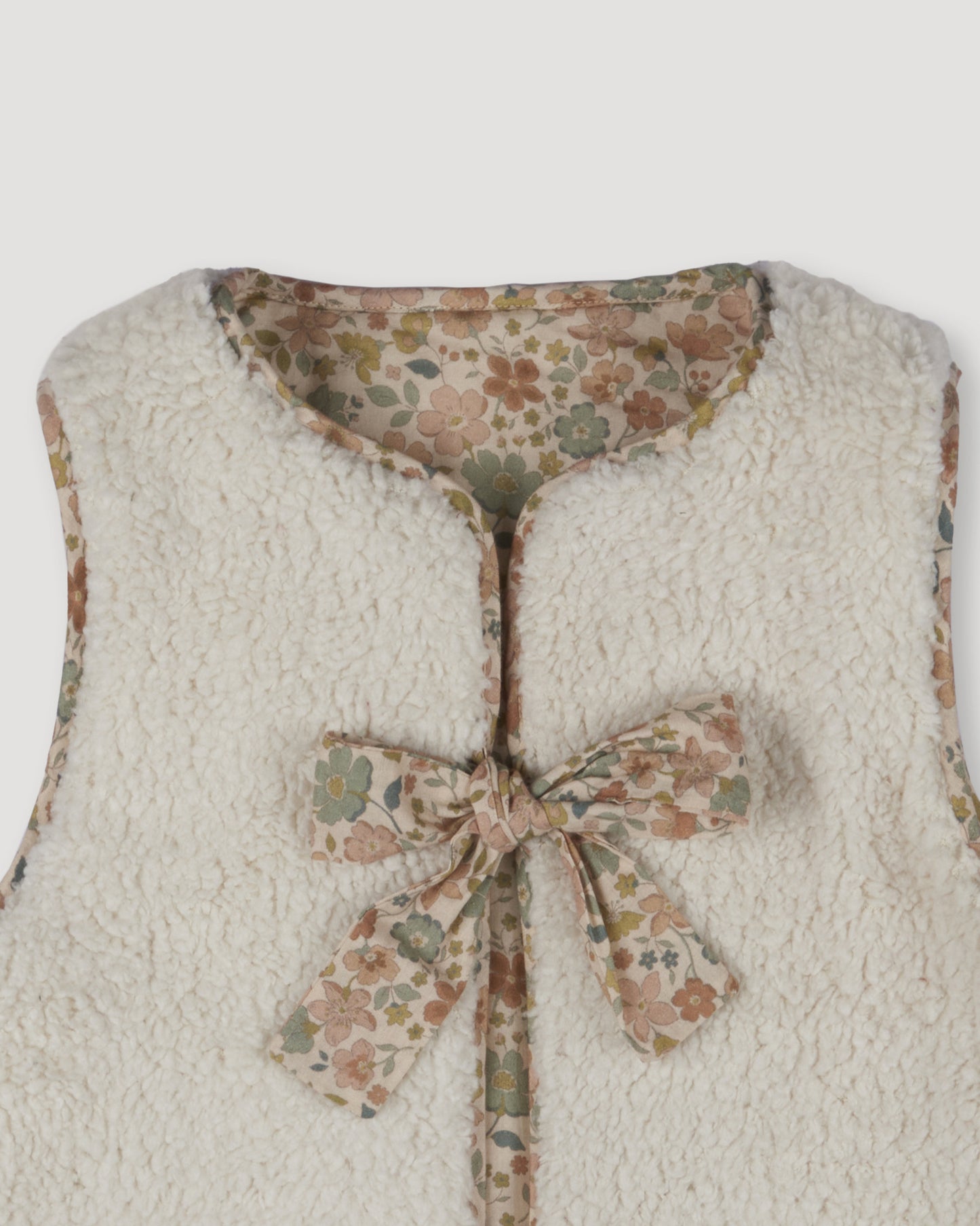 Early Sunday, Milly Baby Quilted Gilet (Reversible) in Garden Flowers print, made from Printed Cotton Cambric fabric, featuring reversible design for versatile styling, shown in a closeup flat-lay view