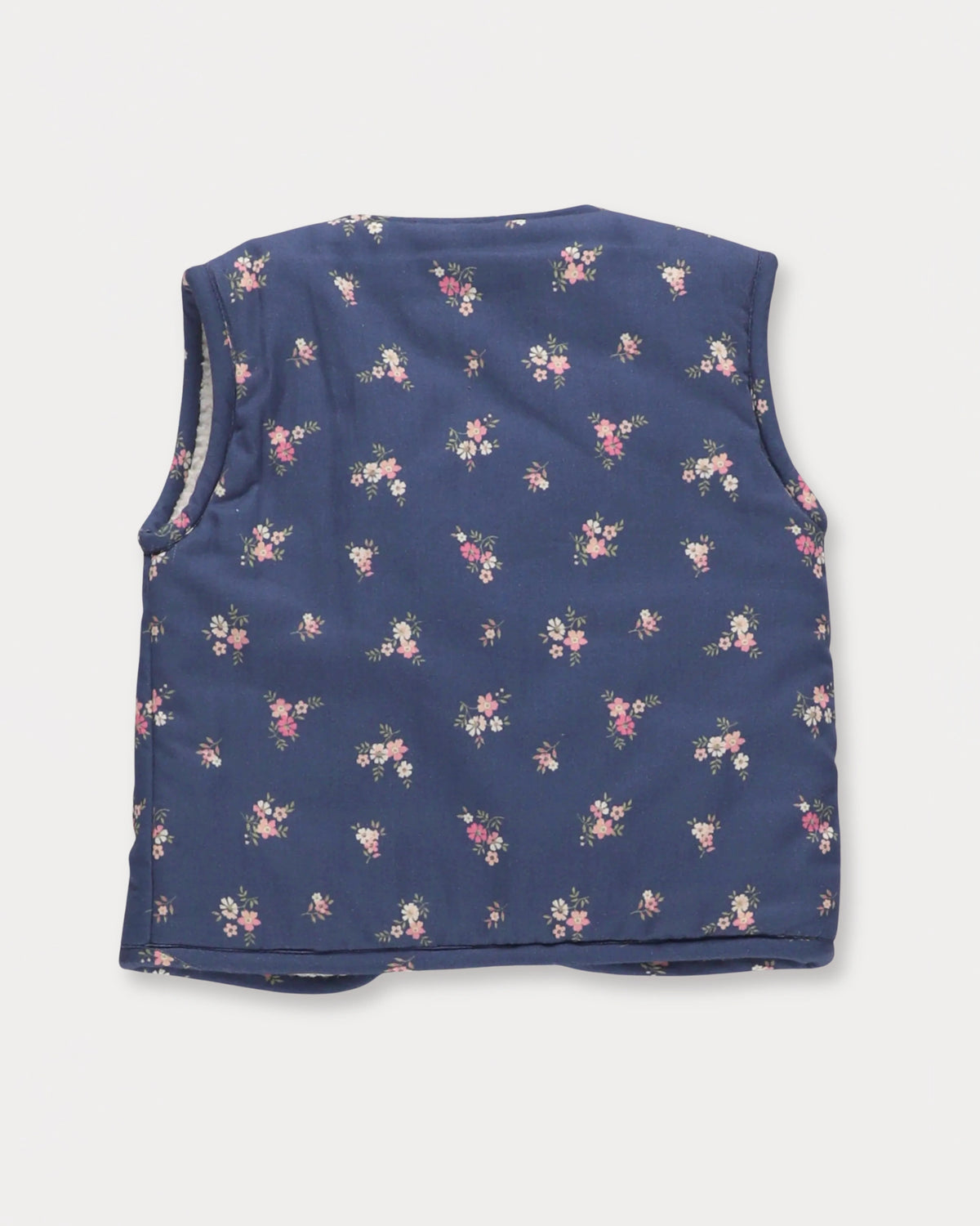 Early Sunday, Milly Baby Quilted Gilet in Ditsy Bouquet Navy, made from Printed Cotton Satin fabric, featuring a sleeveless jacket with a bow tie, shown in a back flat-lay view