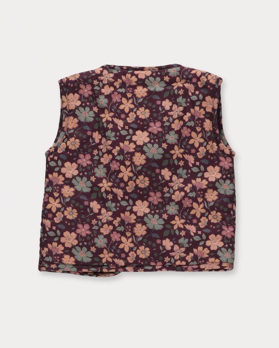 Early Sunday, Milly Baby Quilted Gilet in Garden Flowers Plum, made from Printed Cotton Satin fabric, featuring a sleeveless jacket with a bow tie, shown in a back flat-lay view