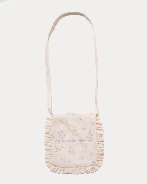 Early Sunday, Miss Sunday Sling in Painted Bouquet print, made from 70% Cotton, 30% Linen fabric, featuring a frill detailed sling purse with flap closure, shown in a back flat-lay view