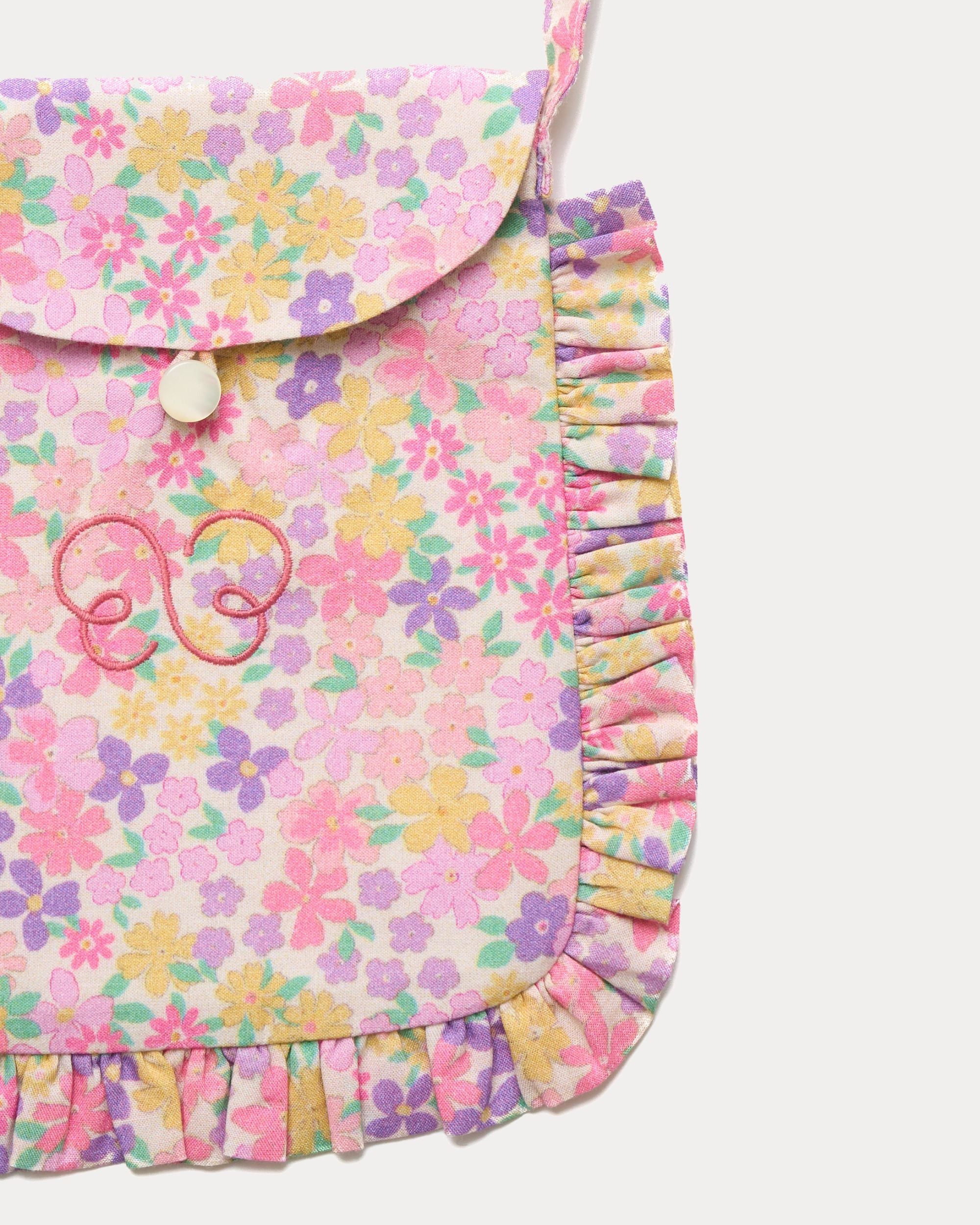 Early Sunday, Miss Sunday Sling in Emma Floral Purple color, made from Organic Printed Cotton Cambric fabric, featuring a frill detailed sling purse with flap closure, shown in closeup flat-lay view