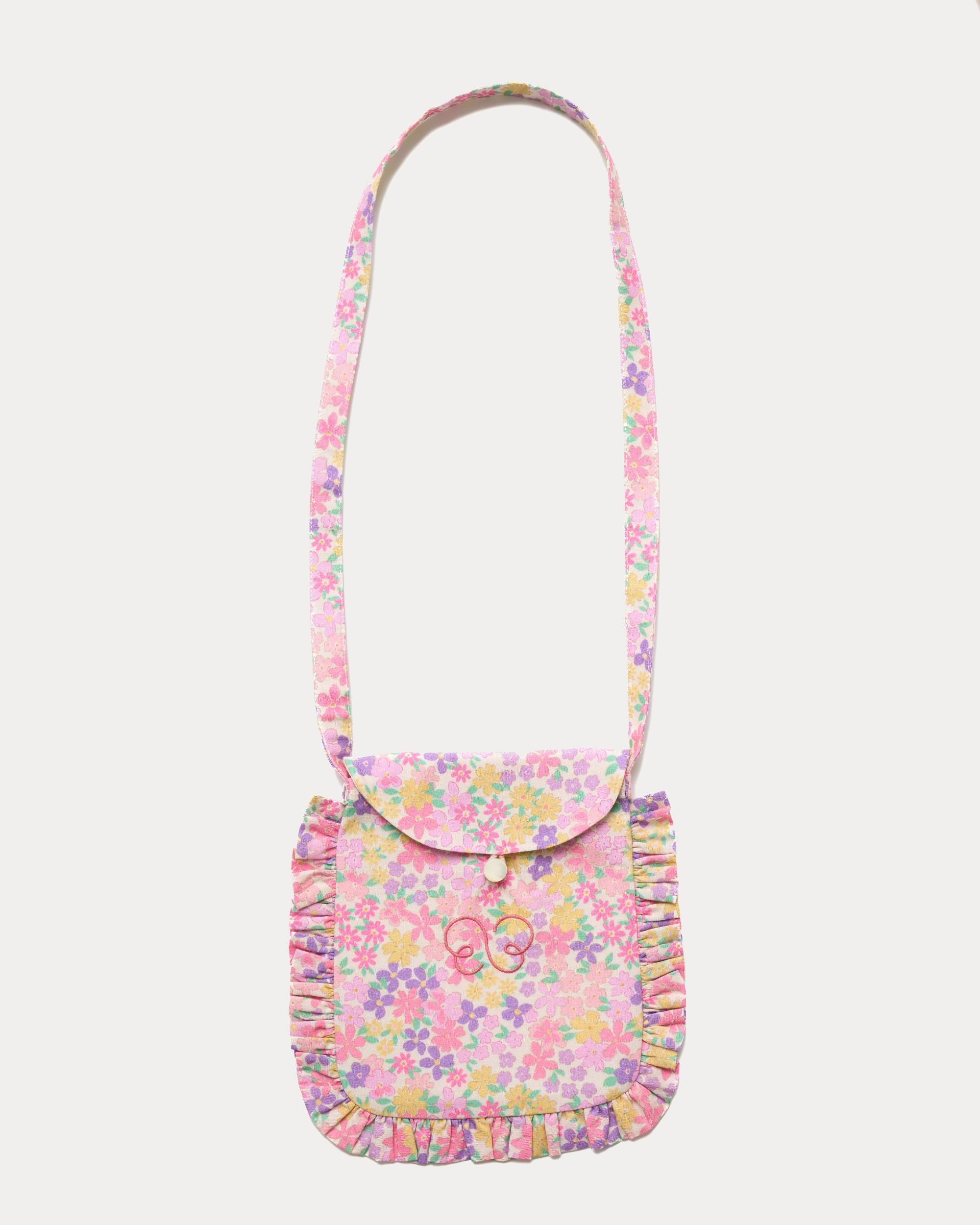 Early Sunday, Miss Sunday Sling in Emma Floral Purple color, made from Organic Printed Cotton Cambric fabric, featuring a frill detailed sling purse with flap closure, shown in front flat-lay view