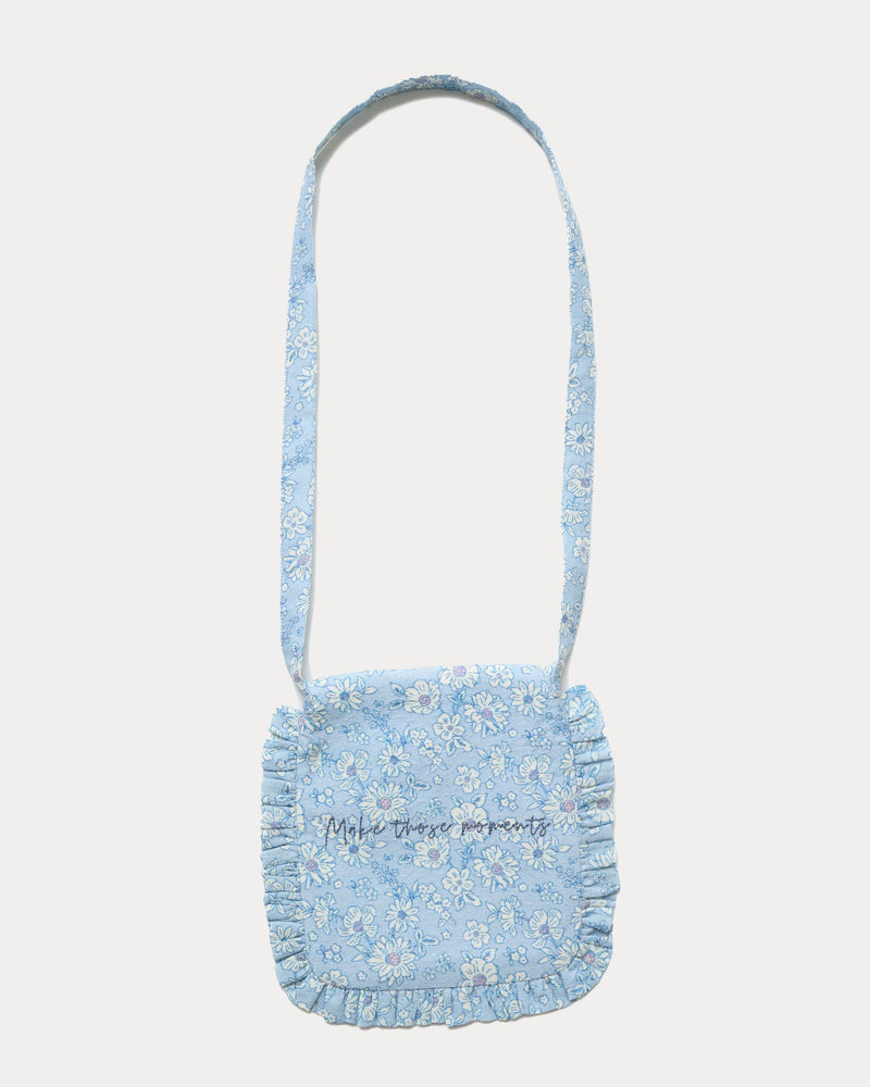 Early Sunday, Miss Sunday Sling in Tonal Floral Blue color, made from Printed Cotton Tiny Swiss Dobby fabric, featuring a frill detailed sling purse with flap closure, shown in back flat-lay view