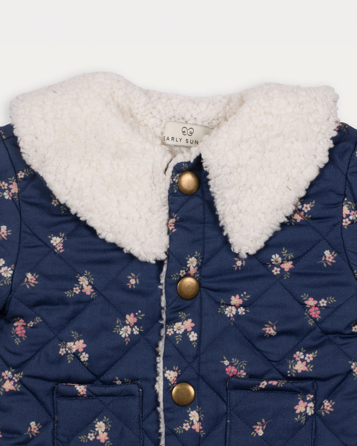 Early Sunday, Molly Baby Quilted Jacket in Ditsy Bouquet Navy, made from Printed Cotton Satin fabric, featuring a sherpa collar & cuffed sleeves with snap button closure, shown in a closeup flat-lay view