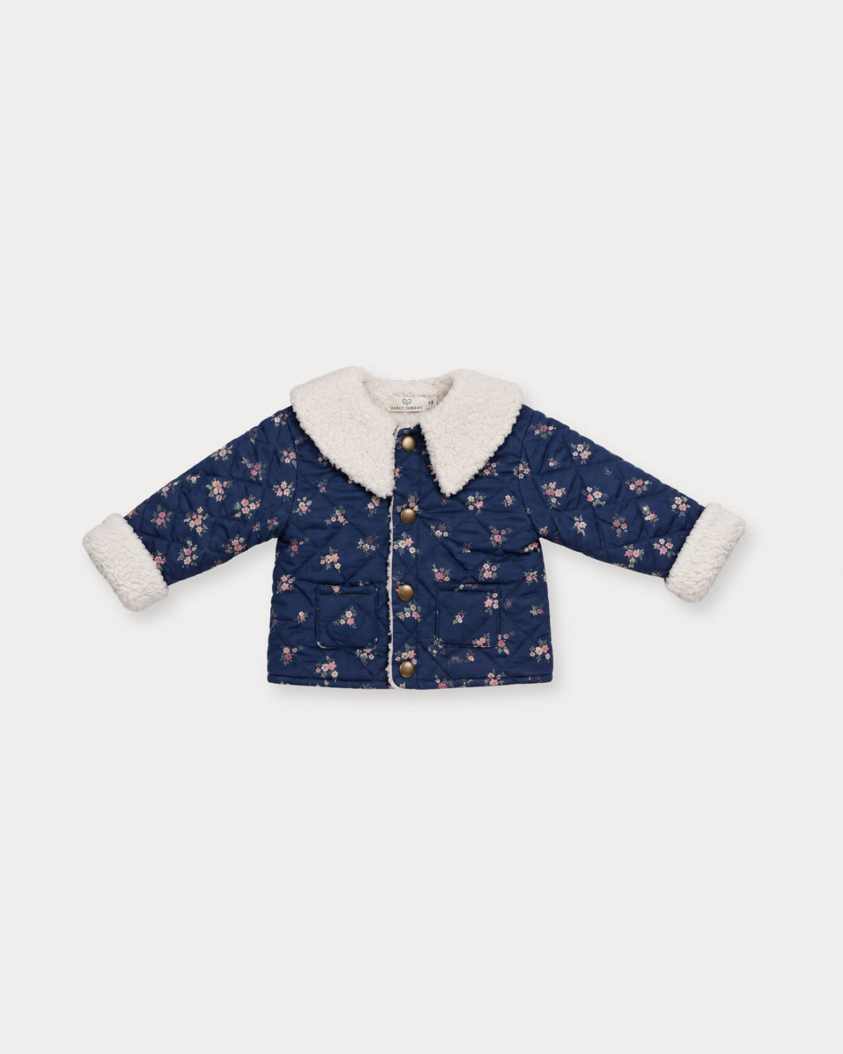 Early Sunday, Molly Baby Quilted Jacket in Ditsy Bouquet Navy, made from Printed Cotton Satin fabric, featuring a sherpa collar & cuffed sleeves with snap button closure, shown in a front flat-lay view