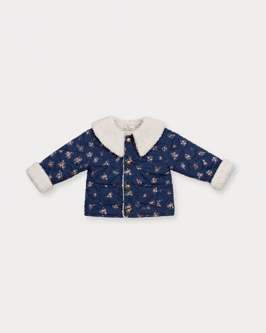 Early Sunday, Molly Baby Quilted Jacket in Ditsy Bouquet Navy, made from Printed Cotton Satin fabric, featuring a sherpa collar & cuffed sleeves with snap button closure, shown in a front flat-lay view