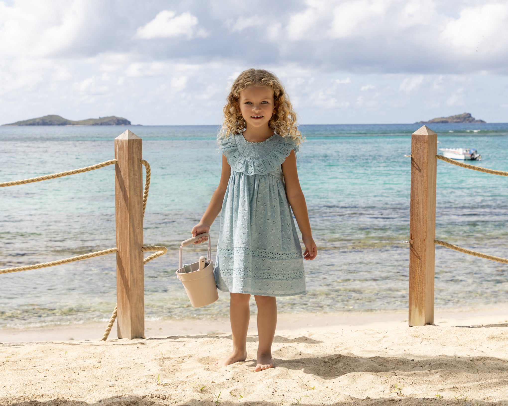 Early Sunday, Natasha Dress in Sea Dream color, made from All-Over Eyelet Embroidered Cotton Schifflie fabric, featuring flattering fit with delicate finishes, combining style and functionality for an effortlessly elegant look, shown in a outdoor shot of model wearing 