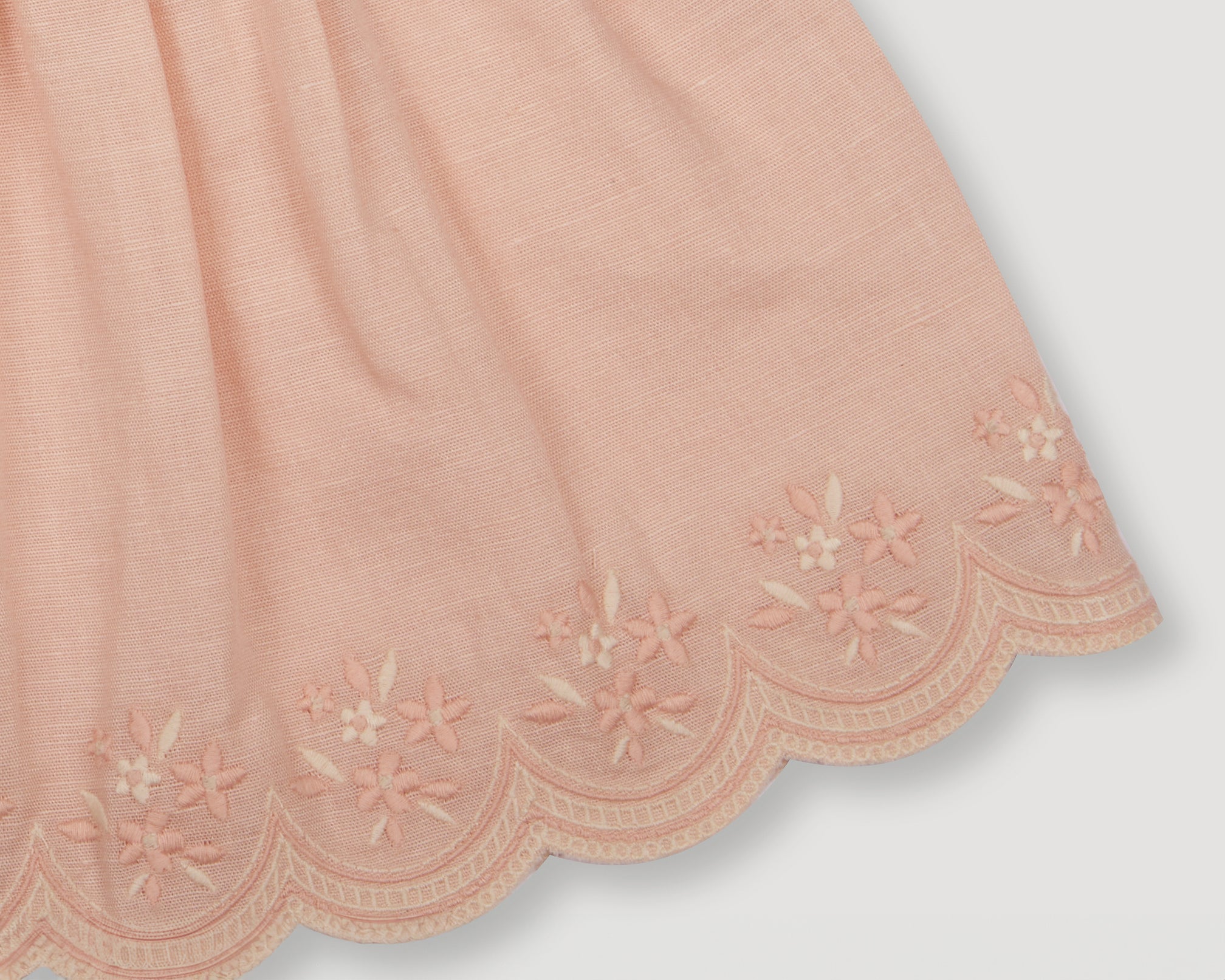 Early Sunday, Olivia Blouse in Pink Sand color, made from Canvas 70% Cotton 30% Linen fabric, featuring smocked bodice for a flexible fit, cross-back strap sand a flared hem, shown in a detailed print view