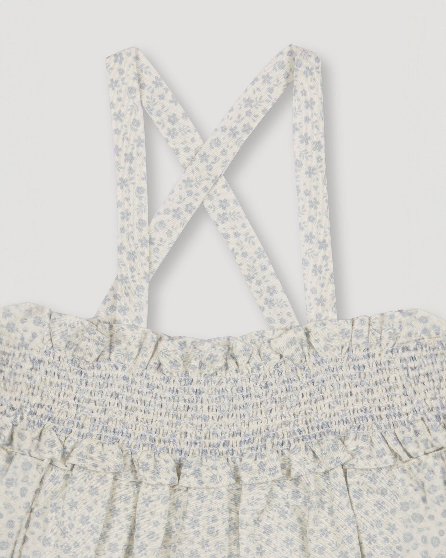 Early Sunday, Olivia Blouse in Mini Flower print, made from Printed canvas 70% Cotton 30% Linen fabric, featuring smocked bodice for a flexible fit, cross-back straps and a flared hem shown in a closeup flat-lay view