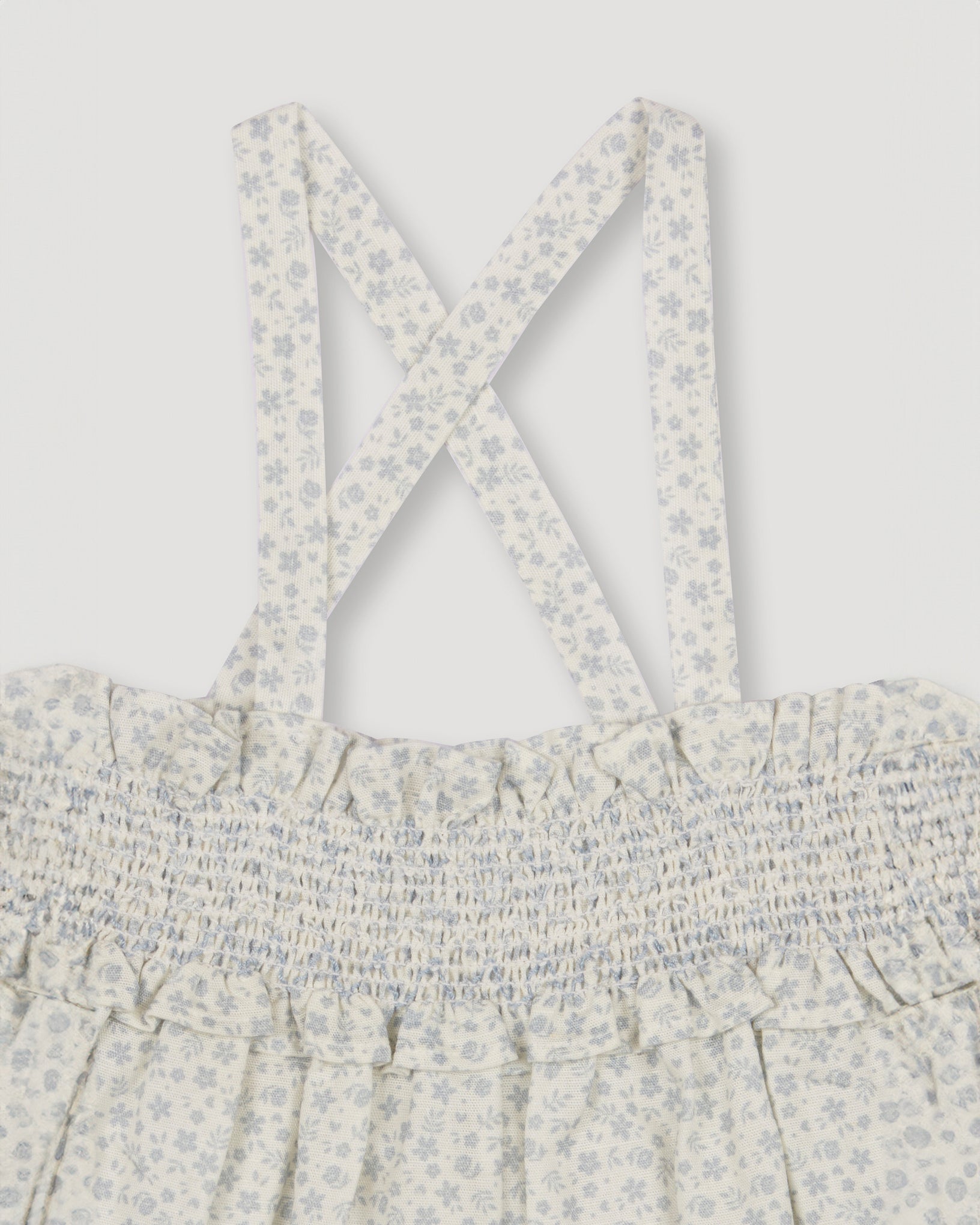Early Sunday, Olivia Blouse in Mini Flower print, made from Printed canvas 70% Cotton 30% Linen fabric, featuring smocked bodice for a flexible fit, cross-back straps and a flared hem shown in a closeup flat-lay view