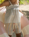 Early Sunday, Olivia Blouse in Mini Flower print, made from Printed canvas 70% Cotton 30% Linen fabric, featuring smocked bodice for a flexible fit, cross-back straps and a flared hem shown in an outdoor shot of model wearing it