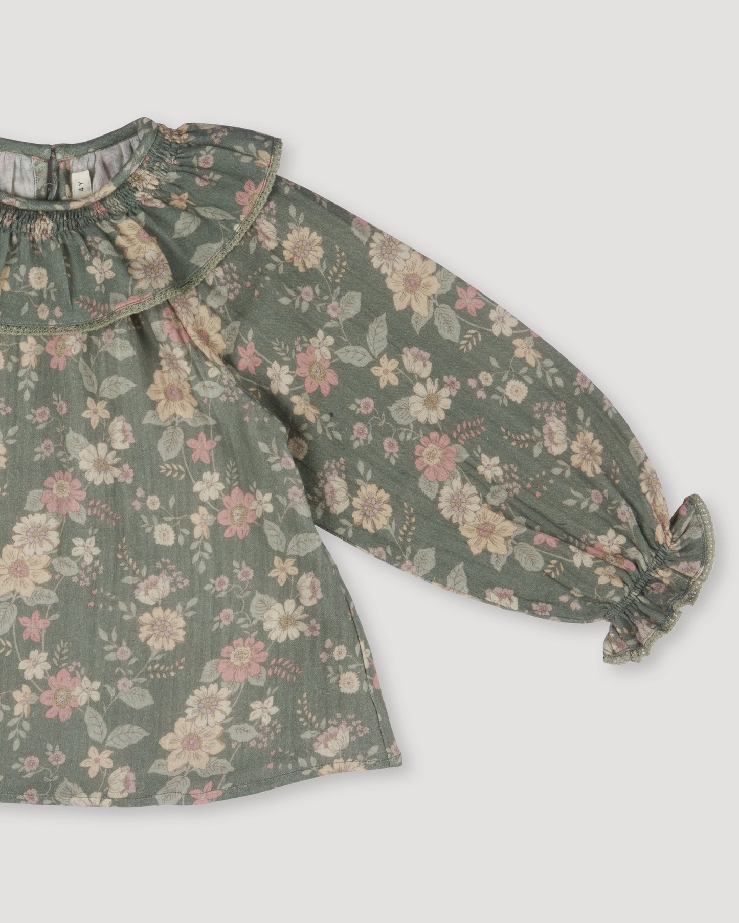 Early Sunday, Paloma Blouse in Autumn Bloom Soft Green, made from Printed Cotton Double Gauze fabric, featuring relaxed fit with a ruffle neckline, shown in a closeup flat-lay view