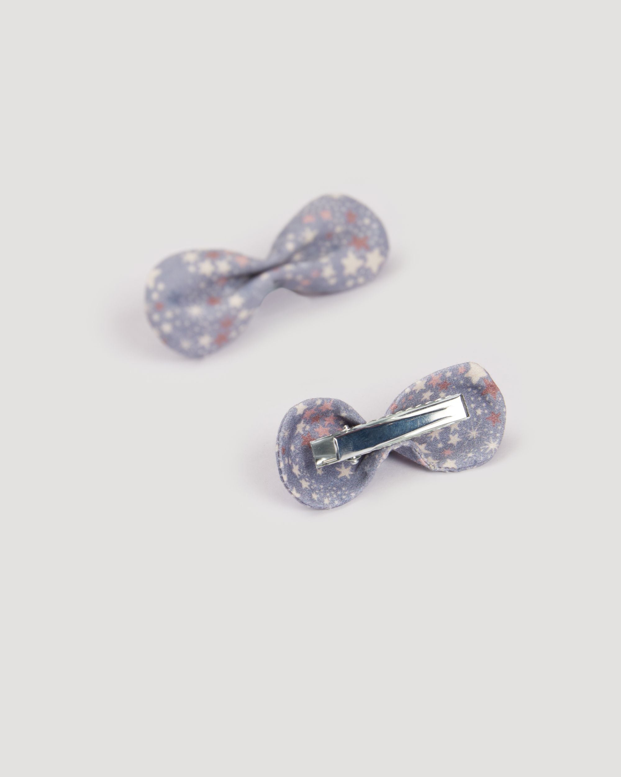 Early Sunday, Penelope Clip in Celestial print, made from Printed 60s Cotton Satin fabric, featuring a set of two bow clips with a secure fit, shown in a back flat-lay view
