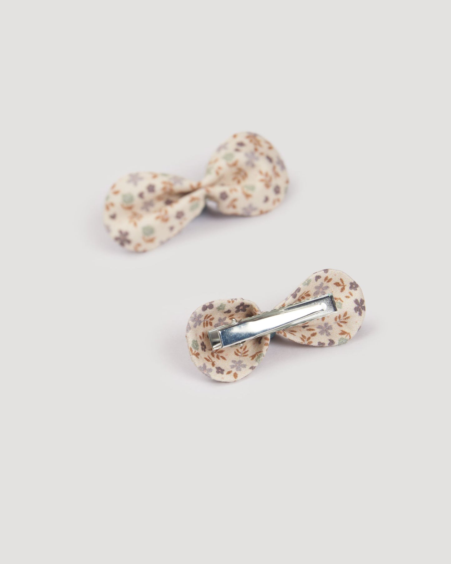 Early Sunday, Penelope Clip in Mini Flowers print, made from Printed 60s Cotton Satin fabric, featuring a set of two bow clips with a secure fit, shown in a back flat-lay view