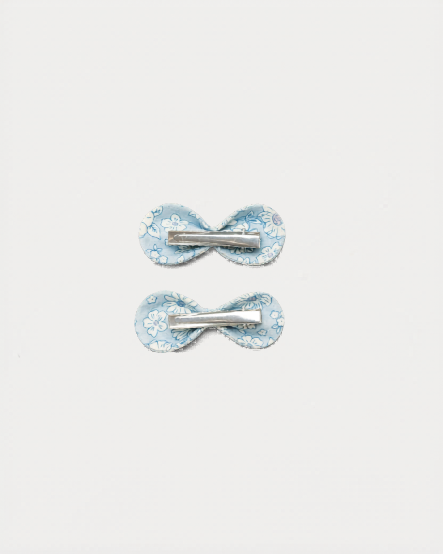 Early Sunday, Penelope Clip in Tonal Floral Blue color, made from Printed Cotton Tiny Swiss Dobby fabric, featuring a set of two bow clips with a secure fit, shown in back flat-lay view