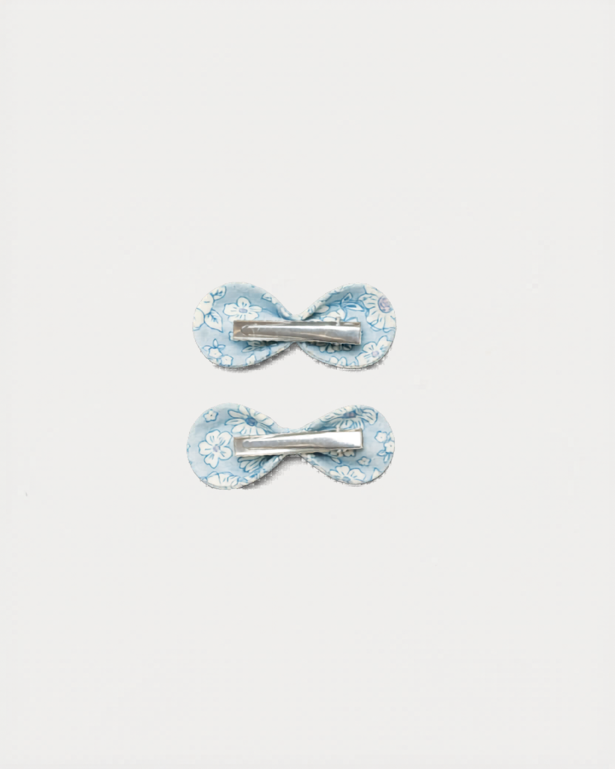Early Sunday, Penelope Clip in Tonal Floral Blue color, made from Printed Cotton Tiny Swiss Dobby fabric, featuring a set of two bow clips with a secure fit, shown in back flat-lay view