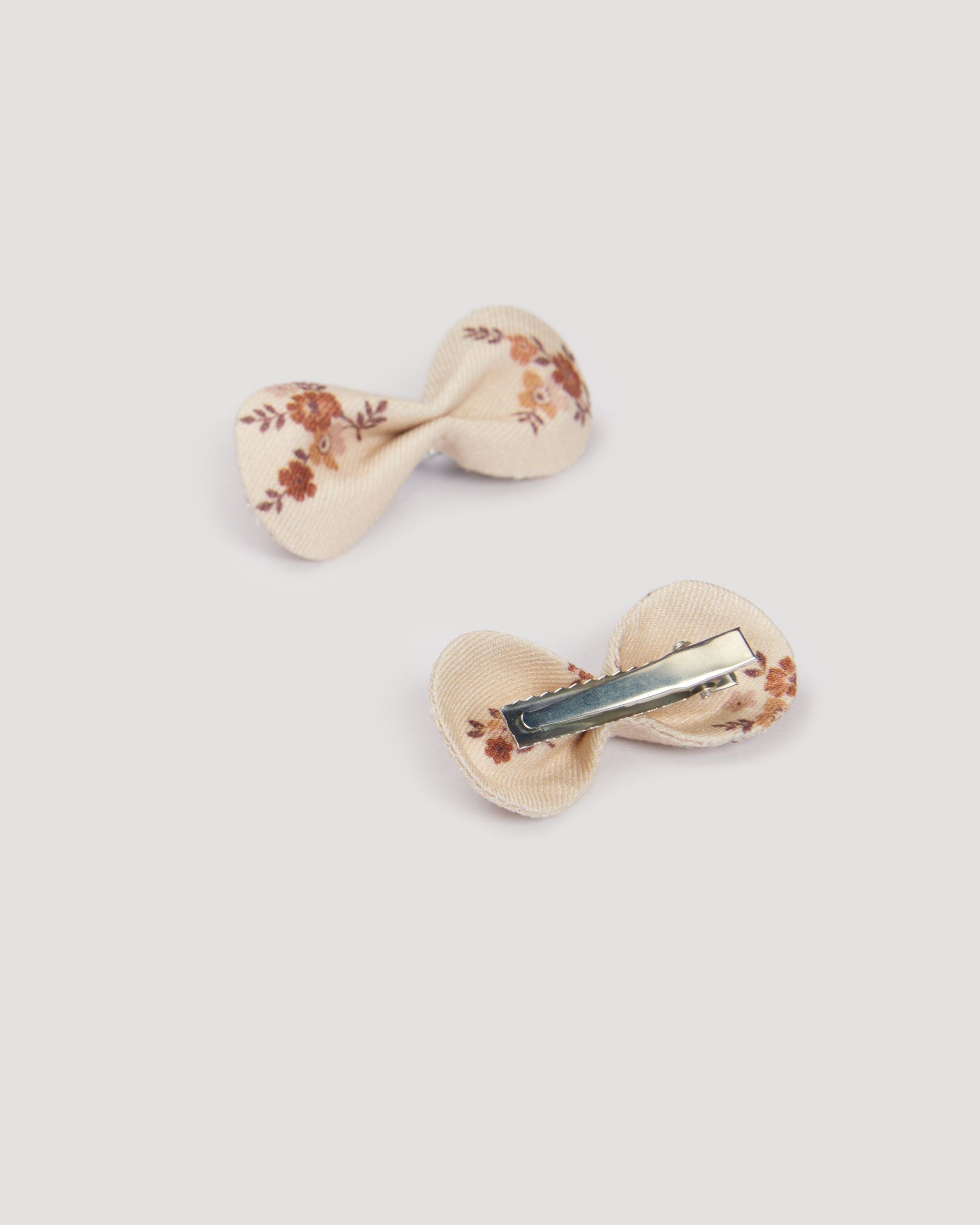 Early Sunday, Penelope Clip in Ditsy Bouquet Cream print, made from Printed Viscose Twill fabric, featuring a set of two bow clips with a secure fit, shown in a back flat-lay view
