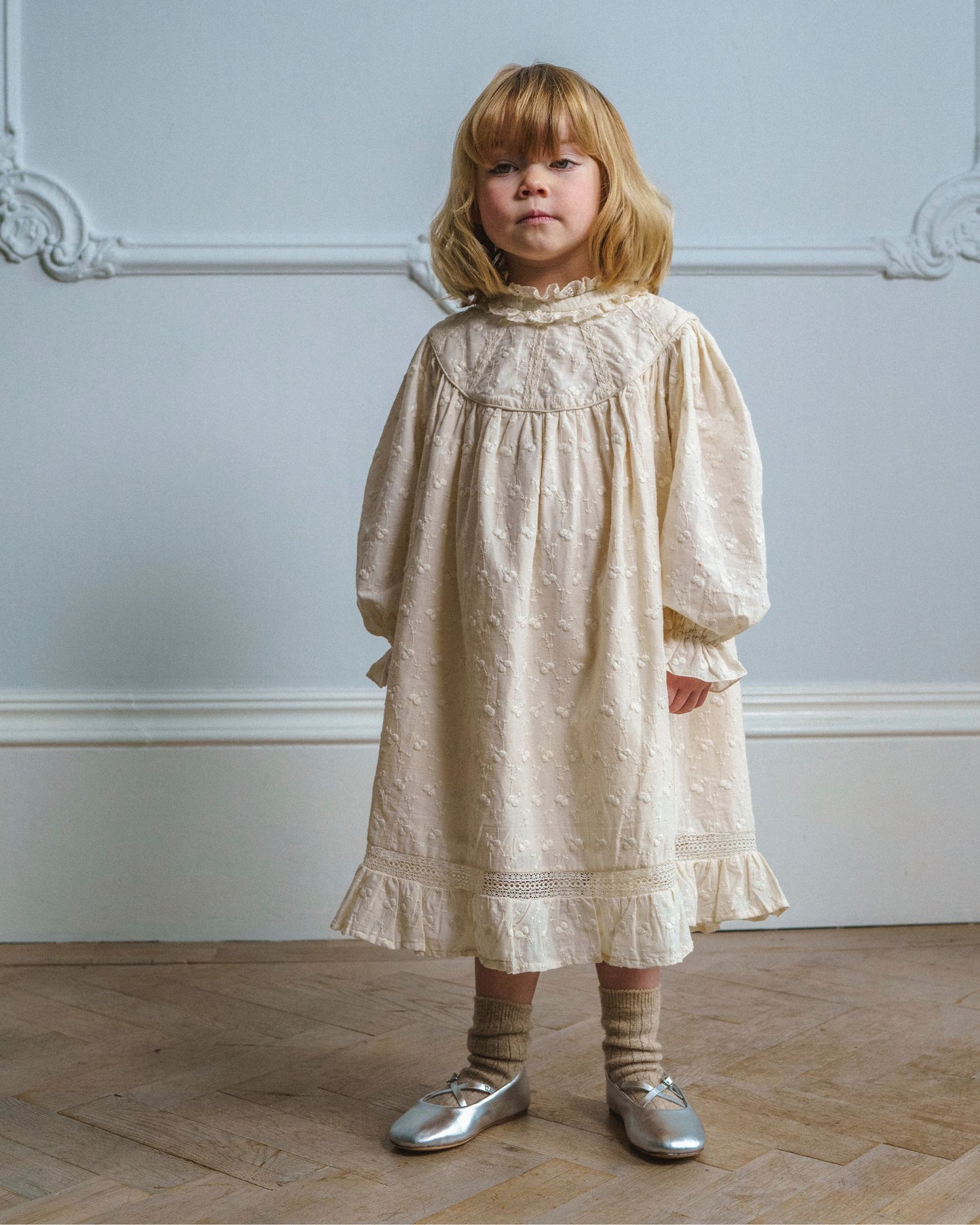 Early Sunday, Penelope Dress in Hazelnut Cream, made from All-Over Embroidered Cotton Cambric fabric, featuring Hand-embroidered floral motifs, shown in a front view of model wearing it